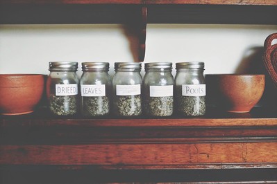 Mason jars labeled with eight different herbs on a kitchen shelf