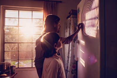 Parent and child tracing figure-8 breathing on a fridge chart