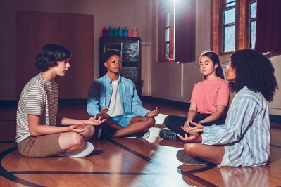 Teen mentors lead a breathing circle in a school gym