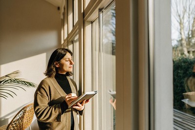 Leader pausing at window with notebook at sunrise