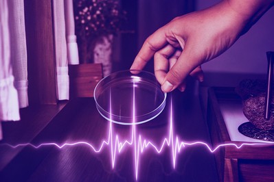 Hand holding a petri dish over a heart waveform with breath mist