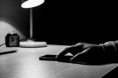 person silencing smartphone at a desk
