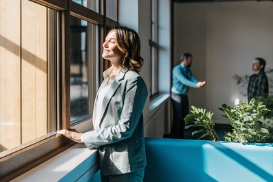 Professional taking a mindful pause by a sunlit office window