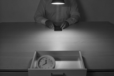 Professional at desk with phone in drawer and analog clock
