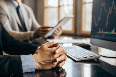 person pausing at a computer with red market charts