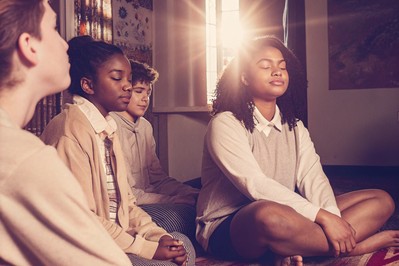 Students in a circle practicing breathing in a colorful classroom