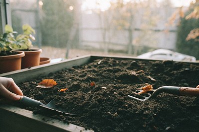 hands sifting dark compost into garden bed